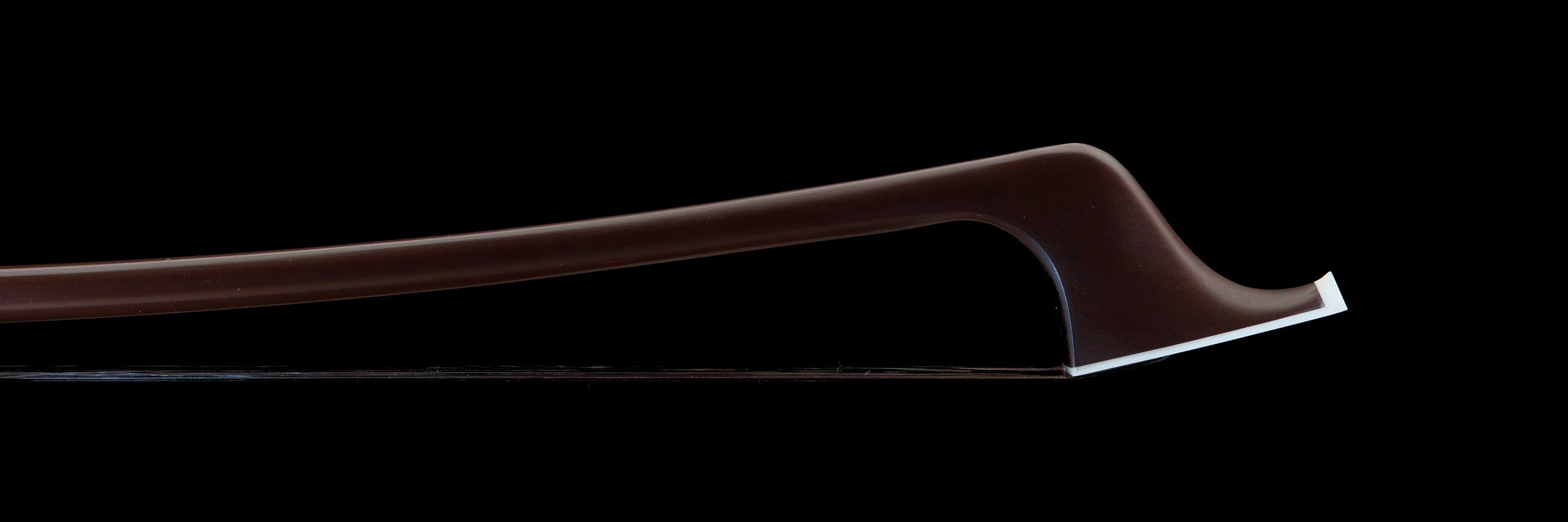 Cette image montre de près la tête de l'archet français de contrebasse, mettant en évidence la courbure raffinée et la finition lisse de la baguette brune. Le design élégant et la qualité de la fabrication sont bien visibles.