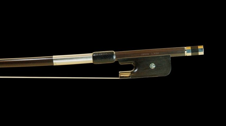 Cette image montre de près la hausse d'un archet français de contrebasse avec une hausse en ébène de 27mm. La hausse en ébène est dotée d'une pastille distinctive et d'un grip en cuir noir, offrant une prise confortable et une esthétique élégante.