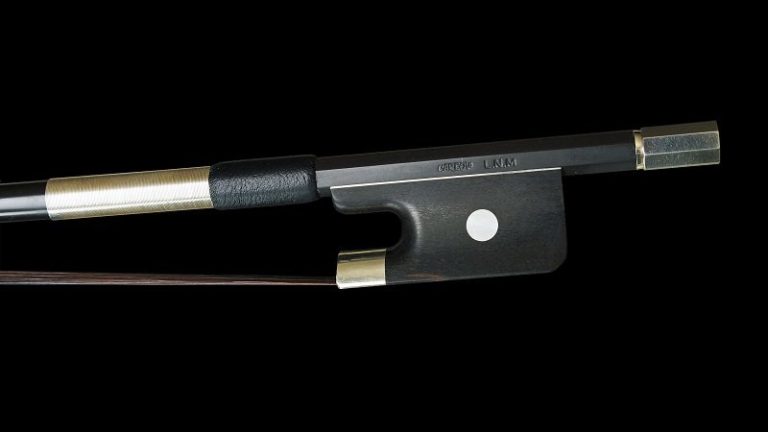 Cette image montre un archet de contrebasse de près, posé sur un fond noir, soulignant ses détails de fabrication. L'archet est en carbone, avec une baguette noire et des finitions en métal argenté. La hausse comporte une pastille blanche distinctive, ajoutant une touche de contraste à l'ensemble. Cet archet de contrebasse est conçu pour offrir une excellente balance et une réponse précise, essentiel pour les musiciens professionnels. Cette image montre un archet de contrebasse de près, posé sur un fond noir, soulignant ses détails de fabrication. L'archet est en carbone, avec une baguette noire et des finitions en métal argenté. La hausse comporte une pastille blanche distinctive, ajoutant une touche de contraste à l'ensemble. Cet archet de contrebasse est conçu pour offrir une excellente balance et une réponse précise, essentiel pour les musiciens professionnels.