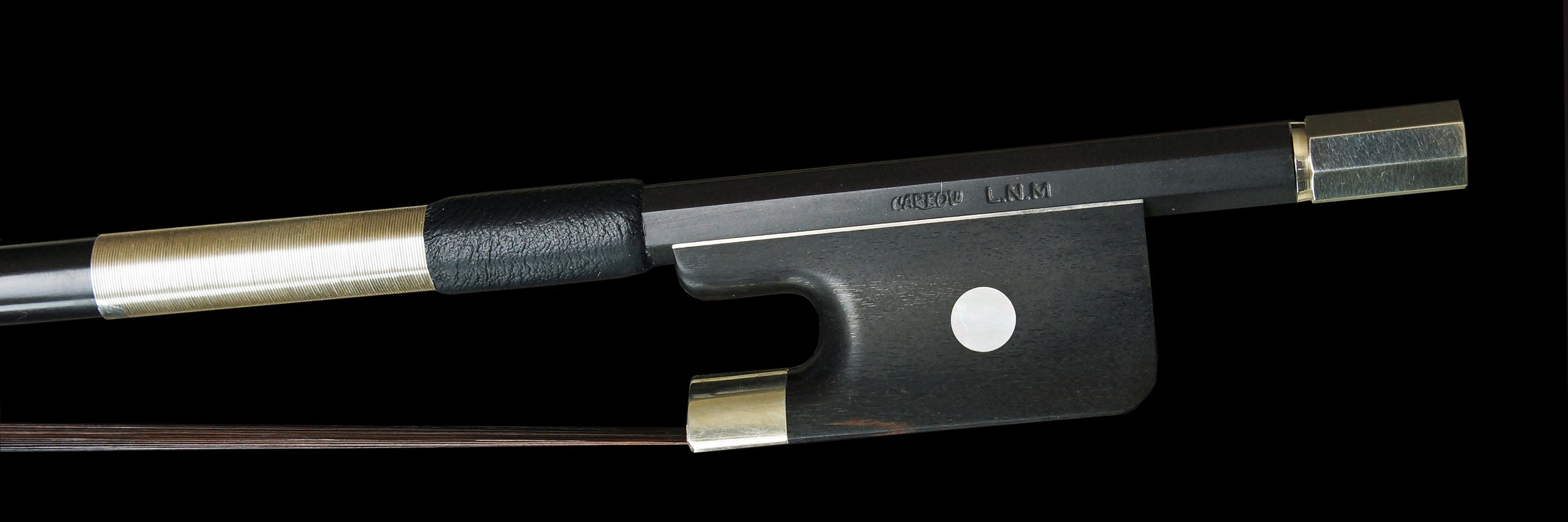 Cette image montre de près un archet de contrebasse en carbone. La baguette noire est ornée de finitions métalliques argentées et la hausse comporte une pastille blanche distinctive, ce qui ajoute une touche de contraste élégante à l'archet.