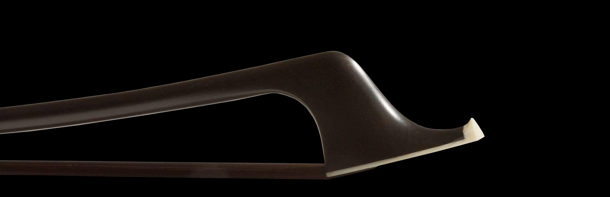 Cette image montre la tête de l'archet de contrebasse français, soulignant la courbure raffinée et la finition lisse de la baguette. La combinaison du bois de serpent et du design élégant en fait un outil essentiel pour les contrebassistes professionnels.