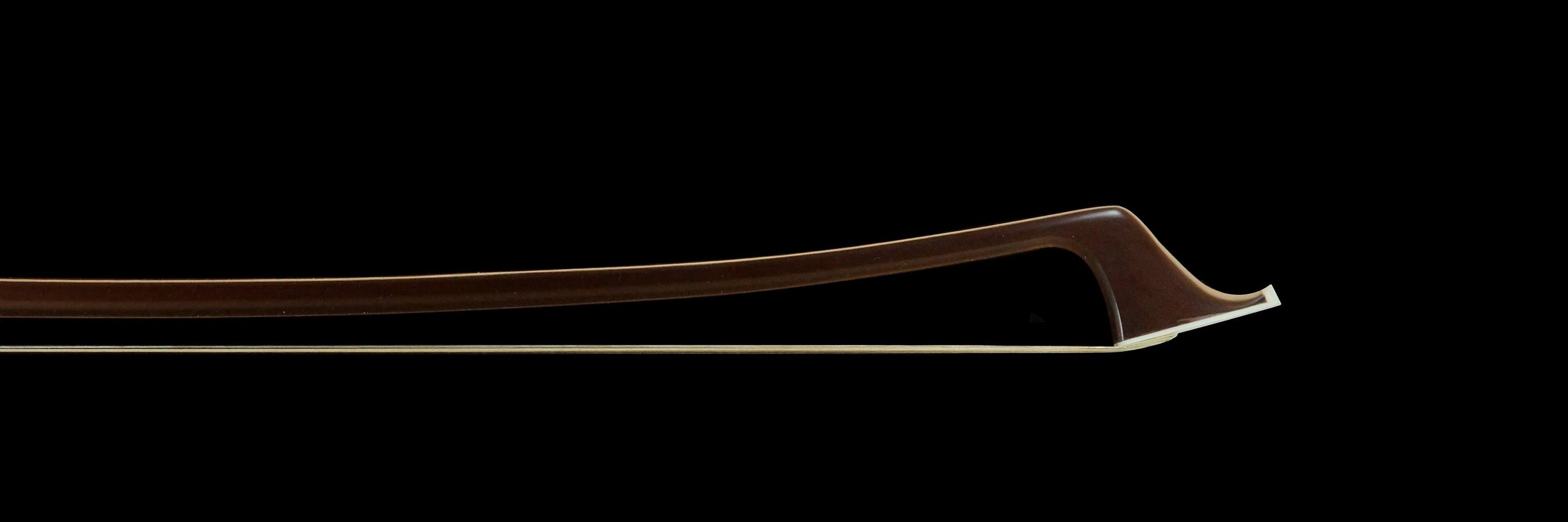 Cette image montre de près la tête de l'archet de contrebasse français, mettant en évidence la courbure raffinée et la finition lisse de la baguette brune. Le design élégant et la qualité de la fabrication sont bien visibles.
