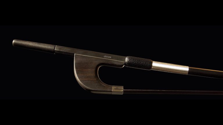 Cette image montre de près la hausse d'un archet de contrebasse allemand en bois d'ébène. La hausse est élégamment conçue avec des finitions métalliques et un grip en cuir noir, offrant une prise confortable et sécurisée.