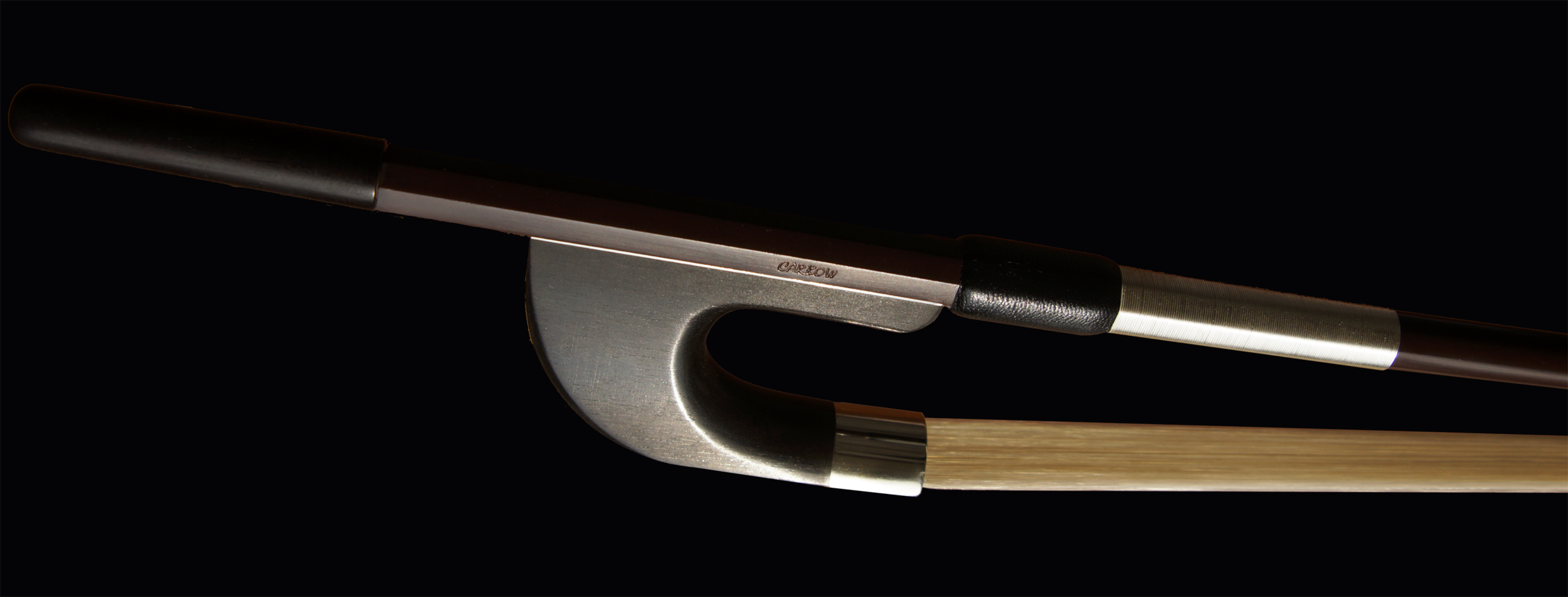 Cette image présente l'archet de contrebasse allemand avec une hausse en ébène sous un autre angle, mettant en évidence la combinaison harmonieuse de matériaux de haute qualité. La baguette brune et la hausse en ébène, associées aux finitions métalliques, soulignent l'élégance et la fonctionnalité de cet archet.