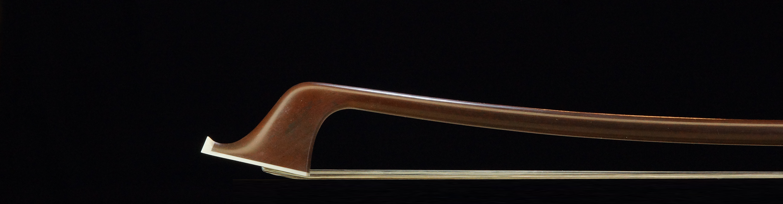Cette image montre la tête de l'archet de contrebasse allemand, soulignant la courbure raffinée et la finition lisse de la baguette. Le design élégant et la fabrication en ébène font de cet archet un choix idéal pour les contrebassistes professionnels, garantissant une performance optimale et une réponse précise.